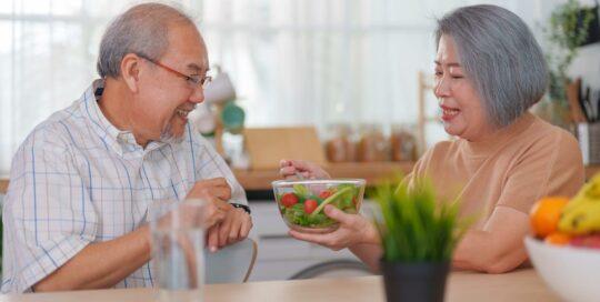 A woman feeding her husband a healthy meal