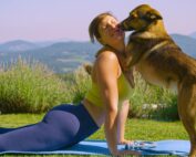 A woman being interrupted mid-yoga pose by her dog